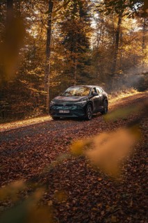 Car on a leafy path in autumn forest, flooded with sunlight, electric car VW ID5, Gechingen, Black