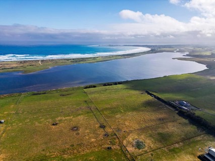 A stunning aerial view captures a coastal lake seamlessly blending into the ocean under a clear