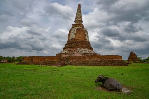 A scene featuring an ancient pagoda under a dramatic cloudy sky in Chiang Mai, Thailand. Nearby, a