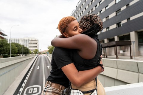 A loving LGBT multiethnic couple shares an affectionate embrace on a city street bridge, capturing