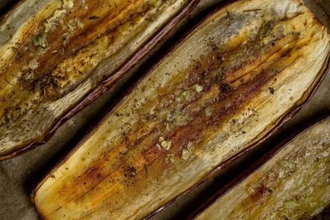 Close-up of baked eggplant slices seasoned with spices, showing a rustic texture. Perfect for