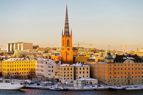A winter view of Stockholm's historic waterfront, showcasing snow-dusted buildings and a prominent