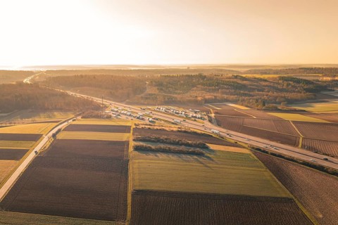 Aerial view of a vast landscape with a busy highway, fields and a warm sunset, A8 near Wurmberg,