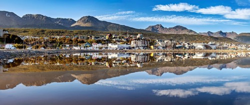 Panoramic shot of a city and mountain landscape with a dramatic reflection in the calm water, The