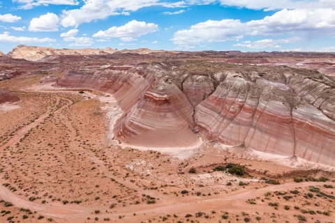 Drone shot capturing the expansive and multi-hued terrain of Hanksville, Utah, featuring striking