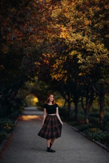 A woman strolls through a Quebec park in autumn, surrounded by vibrant foliage. The path is lined