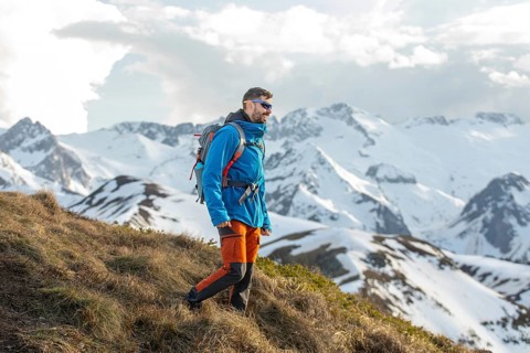 Adventurous man trekking through the stunning snow capped Pyrenees mountains, enjoying nature and