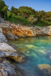 Crystal clear and turquoise water on the beach of Ustrine Bay on a sunny day at sunset on the