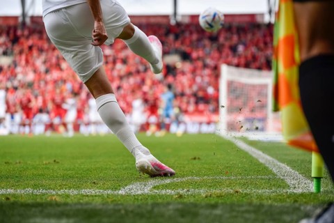 Footballer takes the corner. Detail of player's legs and the ball during soccer match in Lodz,
