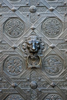 Artfully decorated bronze door with lion's head as a door puller or door knocker on the Gallus