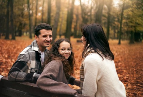 A cheerful family enjoys a day in the park surrounded by autumn leaves. The warm colors and cozy