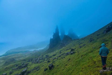 UK. Scotland. Isle of Skye. A tourist looking at the Old Man of Storr during a storm
