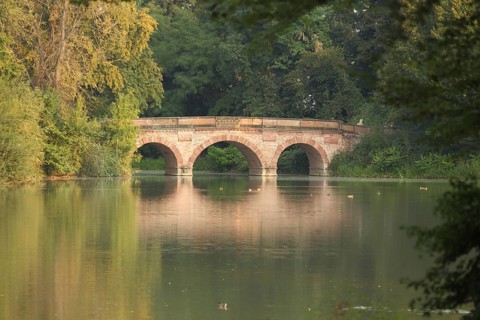 Red bridge on the pond landscape, stone arch bridge, autumn colors, Schönbusch Landscape Park,