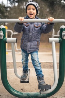 Young boy smiling and exercise at the outdoor gym in Wroclaw, Poland