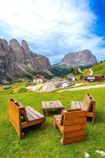 Wooden benches and tables provide a resting spot with breathtaking views of the gardena pass and
