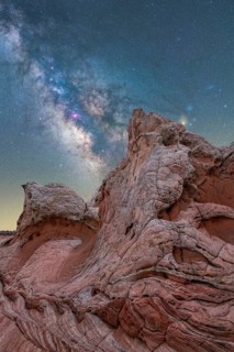 A breathtaking night sky filled with the Milky Way galaxy stretches above uniquely textured rock