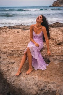 A brunette Caucasian in a pink dress, on the beach having fun by the sea