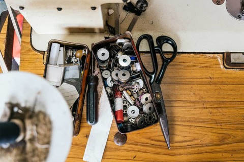 A collection of sewing tools and supplies, including scissors, spools, and a screwdriver, laid out