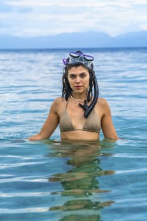 Young woman wearing snorkeling gear enjoys refreshing swim in crystal clear turquoise waters of