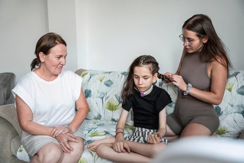 A warm family scene with a disabled girl with a tracheostomy and her caretakers. One is braiding