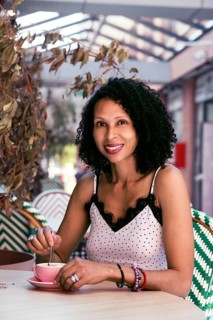 A Mixed-race latin woman in a polka dot top enjoys her coffee at an outdoor cafe, surrounded by a