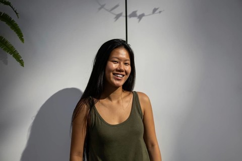 A Chinese woman enjoys the warmth of a summer day in the city. She smiles radiantly, standing
