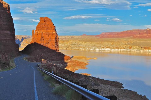 A road leading through a canyon-like landscape with a calm lake, in the light of sunset, Lake
