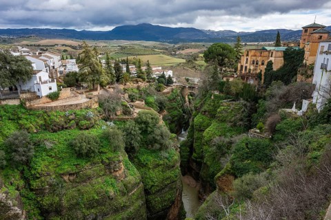 Scenic view looking down into the lush green El Tajo gorge in Ronda, showing the river and the