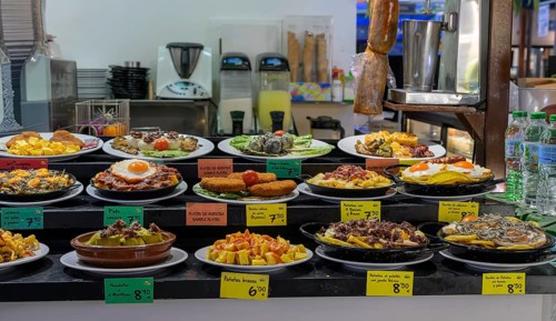 A variety of Spanish tapas on plates in a bar with colorful price tags, Cordoba, Spain