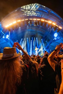 At night at a concert, people with hats, illuminated stage with blue lights and music performance,
