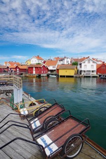 Wooden houses on the water with boats, blue sky with clouds shows a peaceful harbour atmosphere,
