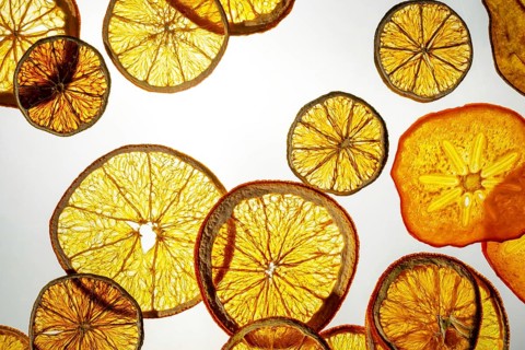 A vibrant display of translucent slices of various dried fruits illuminated from behind. Visible
