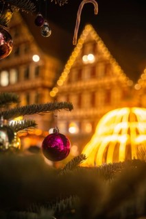 Christmas tree decorated with baubles in front of colourfully illuminated half-timbered houses,