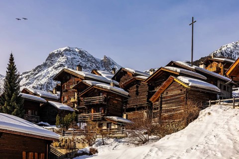 Snow-covered old farmhouses, large wooden cross, historic town center, Grimentz, Val d'Anniviers,