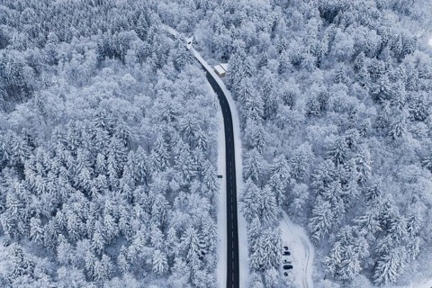 Aerial view of a road in a large, snowy forest, Gechingen, Calw district, Germany