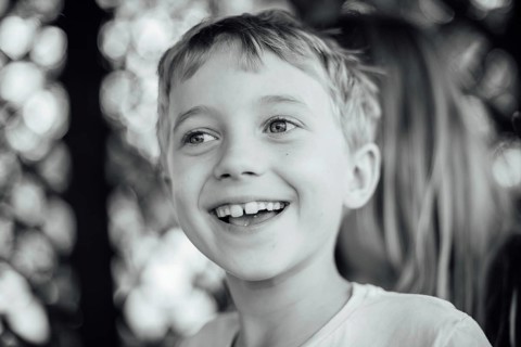 Black and white outdoor portrait of a cute seven years old boy