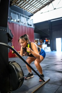 Vertical photo with full length and copy space of a Chinese strong sportive woman pulling weights