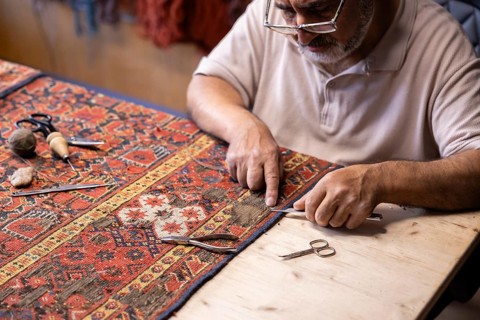 An Iranian carpet-restoration expert works meticulously in his Salzburg workshop, using traditional