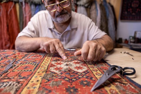 An Iranian master carefully restores an intricate carpet in his workshop in Salzburg, Austria,