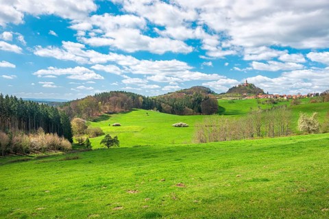 View of hilly landscape with the village of Seitenroda, the Leuchtenburg, green meadows and forests