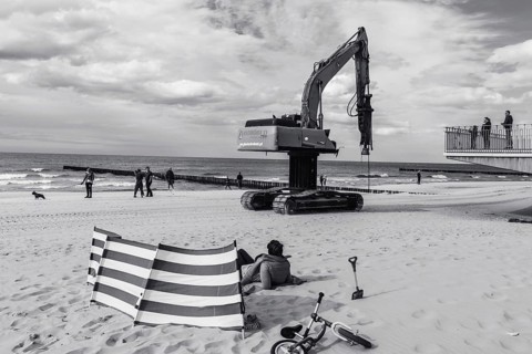 TRZESACZ, POLAND - MAY 1, 2018: The excavator for driving piles goes through the beach with