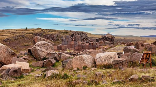 Ruins of stone blocks and large rocks in a grassy landscape under a blue sky, The Chullpas of