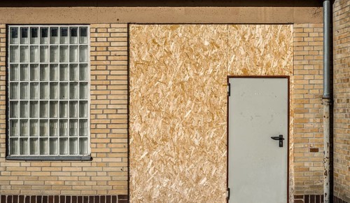 Old building with brick walls and a door covered with OSB panels