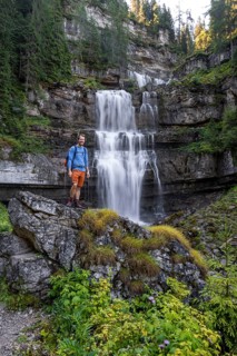 Hiker standing in front of Cascata di Mezzo waterfall, long exposure, Vallesinella, Brenta,