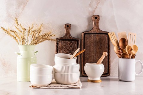 A collection of rustic wooden kitchen utensils, cutting boards, and white ceramic bowls arranged