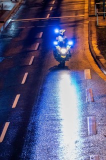 Policeman with motorbike, in rainy weather, blocking a road, police motorbike with blue light