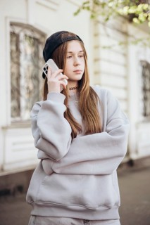 Teenage girl wearing a casual outfit and a cap, holding a smartphone to her ear, standing outside