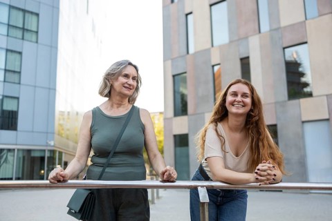 A joyful mother and daughter enjoy a sunny day together in an urban setting. They are smiling and