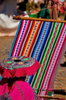 Close-up of a traditional weaving process with colorful fabric, elderly traditionally dressed lady