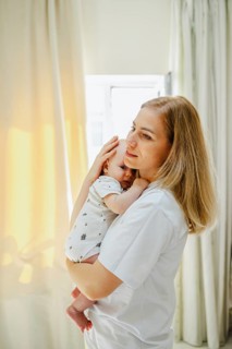 A serene scene of a mother gently holding her baby close, bathed in soft sunlight streaming through